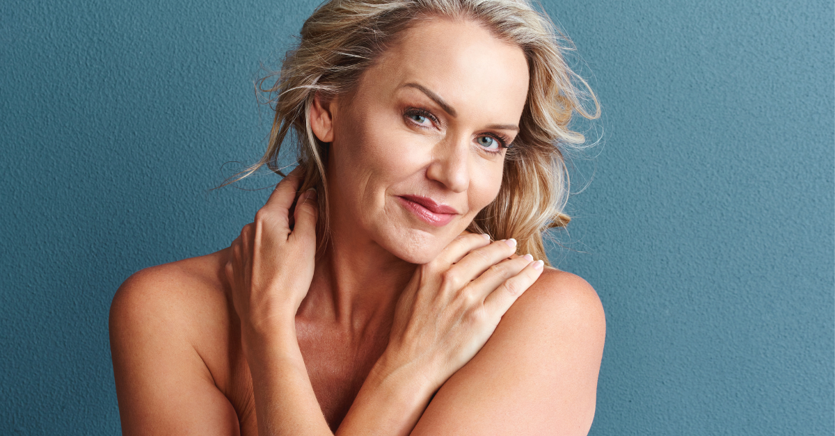 A woman loving herself. She has blonde hair and blue eyes standing on a blue background. 