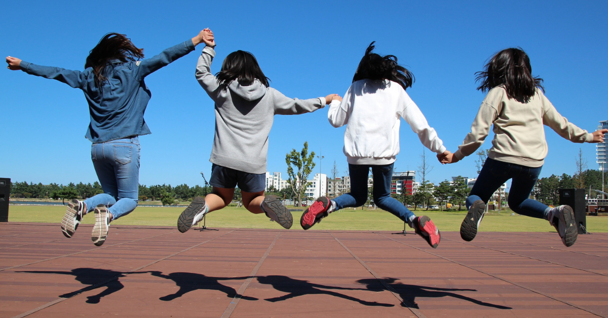 Teeangers holding hands jumping in mid air